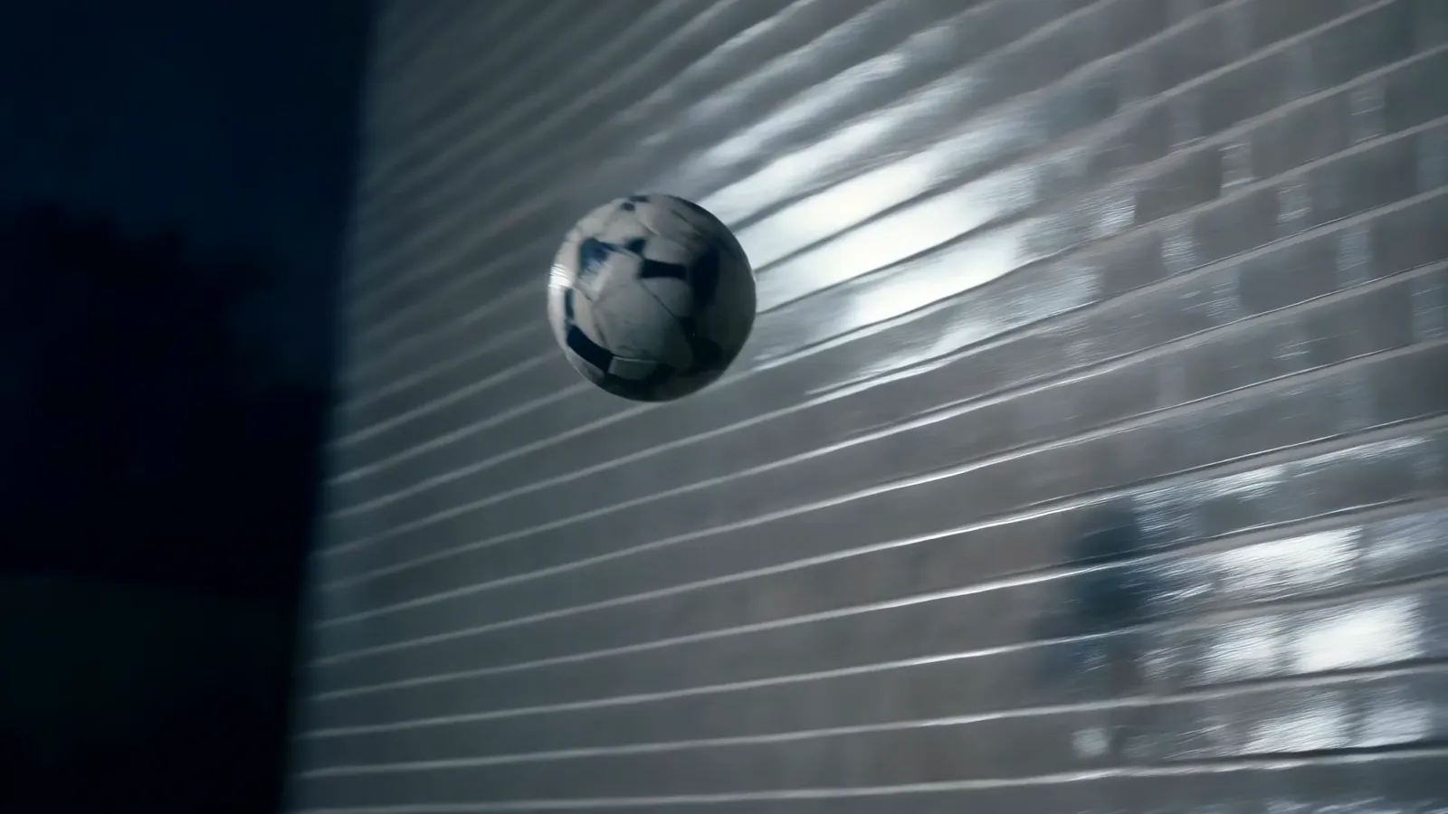 The ball striking the wet brick wall under a floodlight at night